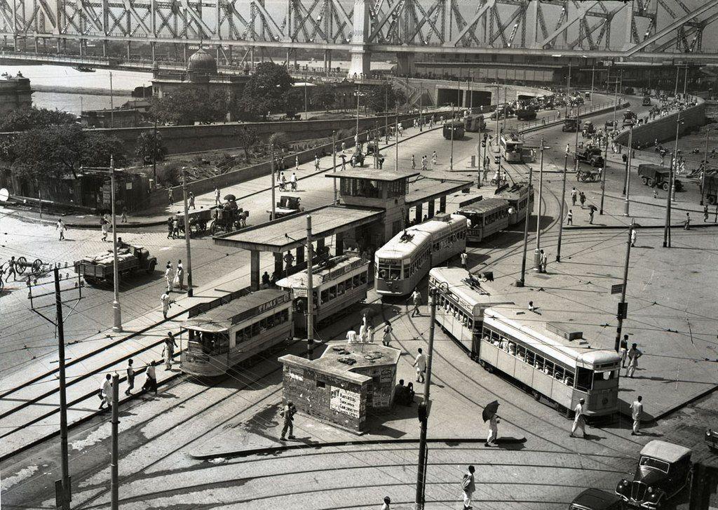 : Vintage photograph of Kolkata trams and Howrah Bridge showing urban life in mid-20th century Bengal,