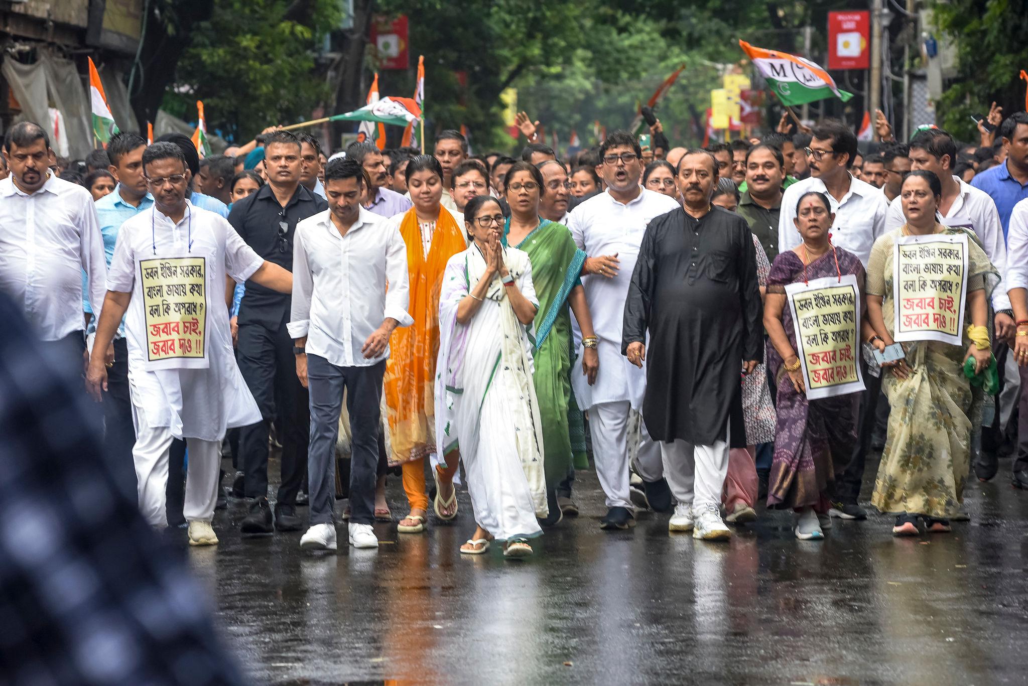 Mamata Banerjee leading a street march with supporters holding placards in Kolkata,